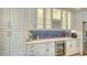 Elegant kitchen featuring white cabinetry, blue tiled backsplash, and marble countertops with a built-in wine cooler at 4741 Pinnacle Dr, Bradenton, FL 34208