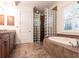 Bathroom featuring a soaking tub, glass block shower, and warm earth tone tiling at 4915 Old Tree Pl, Sarasota, FL 34233