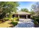 Charming single-story home with a tile roof, lush landscaping, and a brick paver driveway leading to a three-car garage at 4915 Old Tree Pl, Sarasota, FL 34233