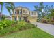 Two story home with yellow siding, brown shutters, manicured landscaping, and a paver driveway, perfect for curb appeal at 5522 Cartagena Dr, Sarasota, FL 34233