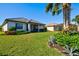 Well-manicured backyard with lush green grass, tropical plants, and a covered patio for outdoor enjoyment at 5590 Rain Lily Ct, Sarasota, FL 34238