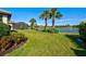 Beautiful backyard featuring a lake view, lush landscaping, and a screened-in patio at 5590 Rain Lily Ct, Sarasota, FL 34238