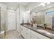 Bathroom features dual sinks with granite countertops, white cabinetry, and a walk-in shower at 5590 Rain Lily Ct, Sarasota, FL 34238