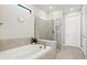 Bathroom with a soaking tub, tiled shower with glass door, neutral walls, and transom window at 5590 Rain Lily Ct, Sarasota, FL 34238