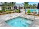 Community hot tub with a paver deck, chairs, and tropical landscaping at 5590 Rain Lily Ct, Sarasota, FL 34238