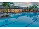 Community pool view with elegant lighting, lounge seating, and tropical landscaping at 5590 Rain Lily Ct, Sarasota, FL 34238