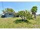 Backyard with a well-maintained lawn, small trees, a glimpse of solar panels, and a patio area for outdoor enjoyment at 568 Sheridan Dr, Venice, FL 34293