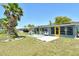 A beautifully landscaped backyard with a vibrant green lawn, mature palm trees, and a cozy patio area with seating at 568 Sheridan Dr, Venice, FL 34293