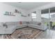 Bright living room features a comfortable gray sectional sofa and sliding glass doors to the outside at 5759 Bungalow Grove Ct, Palmetto, FL 34221