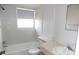 Neutral bathroom features a tub with white tile surround, natural light and a marble countertop sink at 6309 35Th W Ave, Bradenton, FL 34209