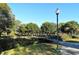 Scenic community park with a charming bridge, paved walkway, mature trees, and a vintage lamp post under a clear blue sky at 640 N Osprey Ave, Sarasota, FL 34236