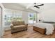 Bright bedroom featuring wood floors, seating, a ceiling fan, and large windows at 6715 Georgia Ave, Bradenton, FL 34207
