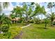 Beautifully landscaped front yard with a stone path, mature trees, and manicured shrubbery enhancing curb appeal at 7340 Villa D Este Drive, Sarasota, FL 34238