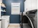 Laundry room featuring a washer and dryer, a deep blue accent wall, and shelving at 8163 Redonda Loop, Lakewood Ranch, FL 34202