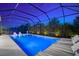 Stunning pool view at dusk featuring lounge chairs, pool lighting, and screened enclosure at 8163 Redonda Loop, Lakewood Ranch, FL 34202