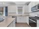 Well-lit kitchen featuring white cabinets, stainless steel appliances, and an island with a sink at 10519 Spring Tide Way, Parrish, FL 34219