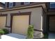 Two car garage on a tan house with brown trim and stone accent with well kept bushes at 11828 Sky Acres Ter, Bradenton, FL 34211