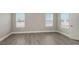 Clean bedroom with wood-look tile flooring, baseboards, and two windows at 12520 Brookgreen St, Venice, FL 34293