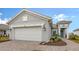 Home exterior showcasing a gray facade, two-car garage, and a brick-paved driveway at 12520 Brookgreen St, Venice, FL 34293