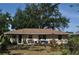 View of the cozy, fenced backyard with wood patio, mature landscaping, and beige home exterior at 1711 30Th W St, Bradenton, FL 34205