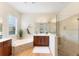Bright bathroom boasts stone accented tub, wood cabinets, glass shower and large window allowing plenty of light at 1727 88Th Nw Ct, Bradenton, FL 34209