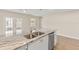 Modern kitchen island featuring granite counters, a stainless-steel dishwasher, and sleek wood floors and a view of the backyard at 2070 Carpetgreen St, Port Charlotte, FL 33948