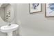 A simple powder room boasts a pedestal sink, circular mirror, and charming floral prints on the wall at 2461 Mellow Ln, Clearwater, FL 33765