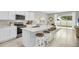 Modern, bright kitchen with stainless steel appliances, white cabinets, a marble countertop island, and tile flooring at 2469 Mellow Ln, Clearwater, FL 33765