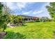 Expansive backyard with lush green lawn, tropical foliage, and screened-in pool area at 27454 Hole In One Pl, Englewood, FL 34223