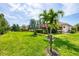 Serene backyard featuring lush lawn, palm trees, and a screened-in pool area with an umbrella at 27454 Hole In One Pl, Englewood, FL 34223