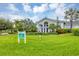 Elegant single-story home with lush landscaping, featuring bright green lawn and palm trees with inviting facade at 27454 Hole In One Pl, Englewood, FL 34223