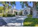 Elegant building entrance with lush landscaping, a circular driveway, and a covered portico at 27454 Hole In One Pl, Englewood, FL 34223