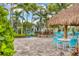 Inviting patio area featuring comfortable seating, a thatched umbrella, and beautiful landscaping at 27454 Hole In One Pl, Englewood, FL 34223