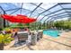 Relaxing screened-in pool area with ample seating, a fire pit, and lush tropical landscaping at 27454 Hole In One Pl, Englewood, FL 34223