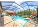 Spacious screened-in pool area with comfortable lounge seating, an umbrella, and lush landscaping at 27454 Hole In One Pl, Englewood, FL 34223