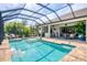 Beautiful screened-in pool area featuring a large pool, lounge chairs, and a well-equipped outdoor kitchen at 27454 Hole In One Pl, Englewood, FL 34223