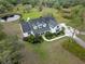 An aerial view displays lush landscaping, a pristine lawn, and a home with a gray roof at 30416 Saddlebag Trl, Myakka City, FL 34251
