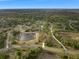 Aerial view of a sprawling property with a pond, mature trees, and a long driveway at 30416 Saddlebag Trl, Myakka City, FL 34251