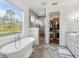 Bright bathroom showcasing a tub, vanity, walk-in shower, and herringbone tile floor at 30416 Saddlebag Trl, Myakka City, FL 34251