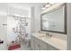 Bright bathroom features a single vanity, large mirror and tub with a modern floral shower curtain at 30416 Saddlebag Trl, Myakka City, FL 34251