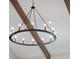 Close up of round metal chandelier with candelabra bulbs against a white ceiling with wooden beams at 30416 Saddlebag Trl, Myakka City, FL 34251