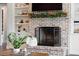 Living room fireplace featuring brick surround, greenery, and built in white shelving around a tv above the mantle at 30416 Saddlebag Trl, Myakka City, FL 34251