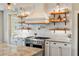 Bright open kitchen featuring stainless appliances, and floating shelves against a white backsplash at 30416 Saddlebag Trl, Myakka City, FL 34251