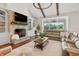Bright living room features a brick fireplace, wood beams, and a large sectional sofa at 30416 Saddlebag Trl, Myakka City, FL 34251