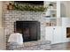 Cozy fireplace with a decorative brick surround and built-in shelving and cabinets at 30416 Saddlebag Trl, Myakka City, FL 34251