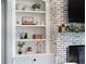 Built in white shelving surrounds a fireplace with brick surround and mantle, and features decor on shelves at 30416 Saddlebag Trl, Myakka City, FL 34251