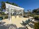Outdoor kitchen featuring a built-in grill under a pergola, surrounded by lush landscaping and comfortable seating at 3420 77Th W St # 202, Bradenton, FL 34209