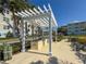 Outdoor kitchen featuring a built-in grill under a pergola, surrounded by lush landscaping and comfortable seating at 3420 77Th W St # 202, Bradenton, FL 34209