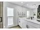 Bright bathroom featuring a white vanity with marble countertop, a large mirror, and a window providing natural light at 3725 Spyglass Hill Rd, Sarasota, FL 34238