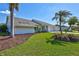 Single-story home featuring a lush lawn, brick driveway, and tropical landscaping with mature palm trees at 3725 Spyglass Hill Rd, Sarasota, FL 34238